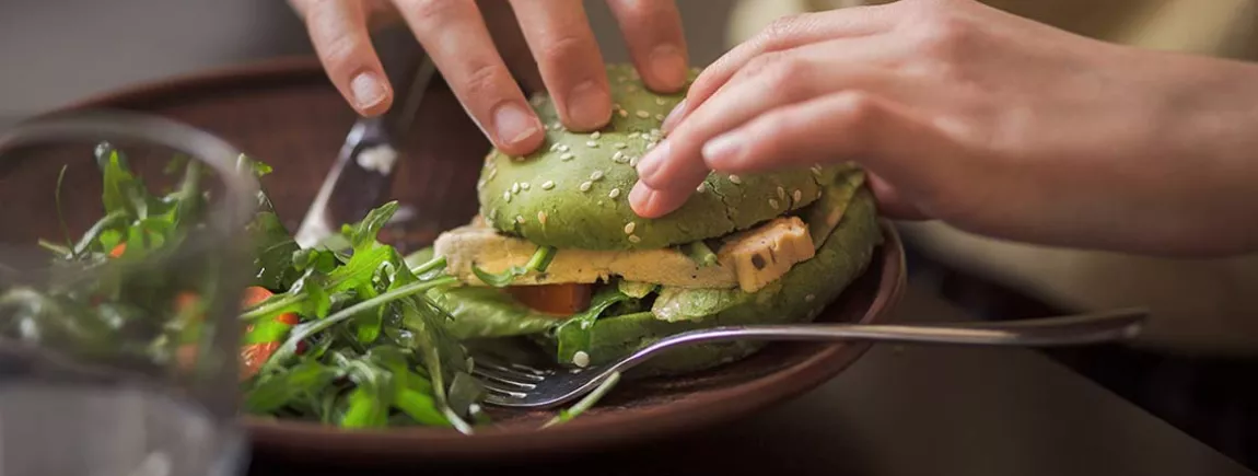 Une personne mangeant un hamburger végatal