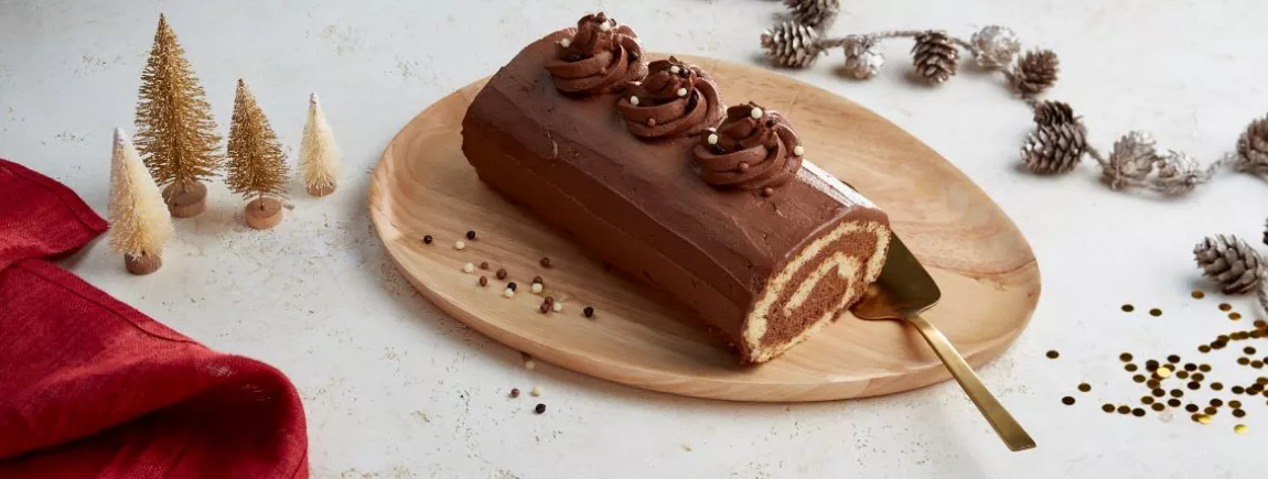 Une buche de noël posée sur une plateau de bois 